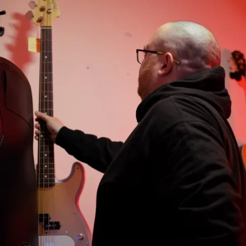 Ash puts a bass guitar back on the wall mount